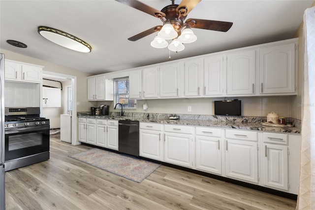 kitchen with light wood-type flooring, dark stone countertops, white cabinets, black dishwasher, and stainless steel range with gas cooktop