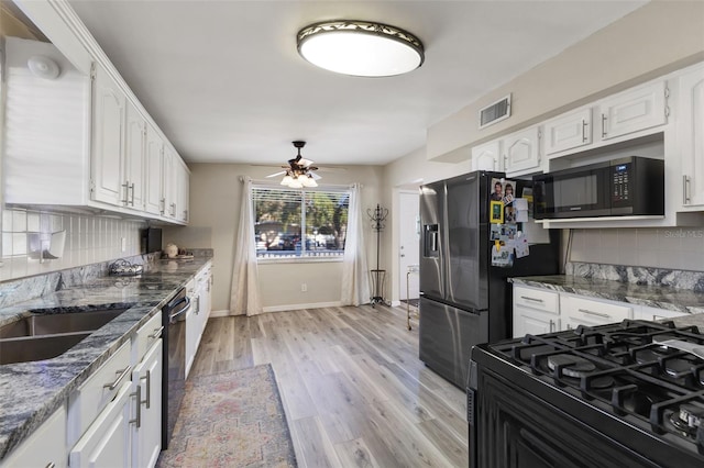 kitchen with black appliances, white cabinets, dark stone counters, and light hardwood / wood-style flooring