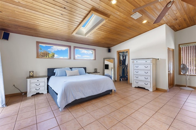 tiled bedroom featuring vaulted ceiling with skylight, a walk in closet, and wooden ceiling