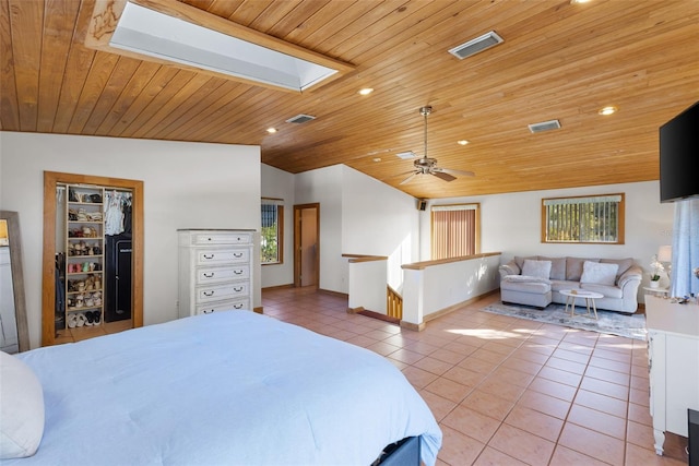 tiled bedroom with lofted ceiling with skylight, a closet, and wood ceiling