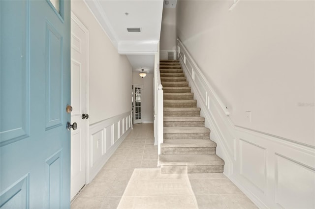 stairs with crown molding and tile patterned floors