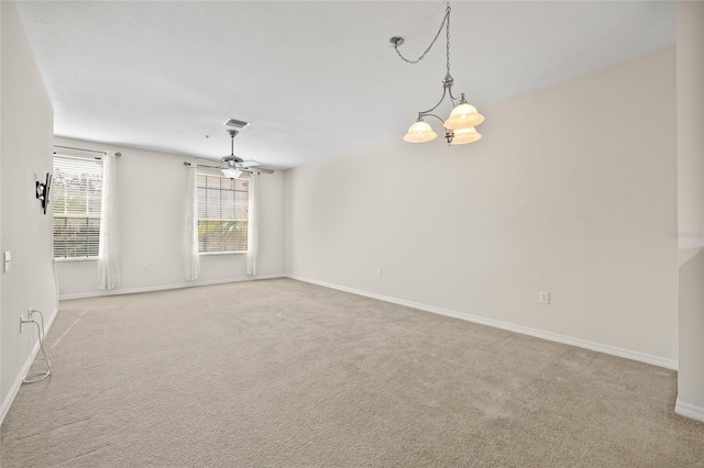 carpeted empty room with ceiling fan with notable chandelier