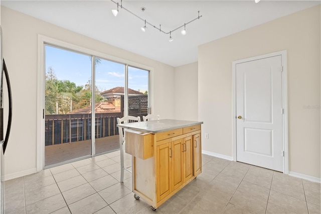 kitchen with rail lighting, a breakfast bar, light brown cabinetry, a center island, and light tile patterned floors