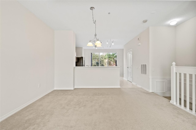 carpeted empty room featuring a chandelier