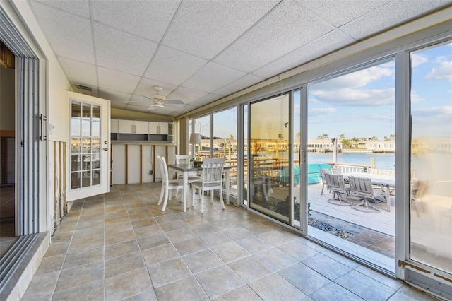 unfurnished sunroom with a paneled ceiling, ceiling fan, a water view, and a wealth of natural light