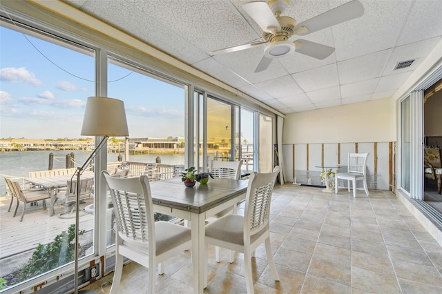 sunroom featuring a paneled ceiling, ceiling fan, a water view, and a healthy amount of sunlight