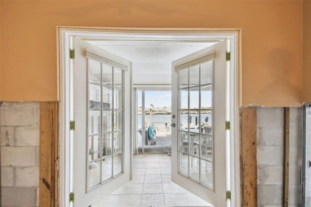 doorway to outside with french doors, a water view, and light tile patterned flooring