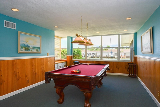 recreation room with a textured ceiling, dark carpet, wood walls, and pool table