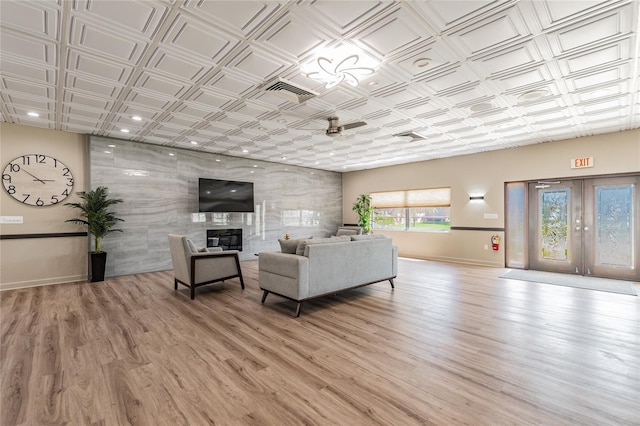 living room with ceiling fan, light wood-type flooring, and a tile fireplace