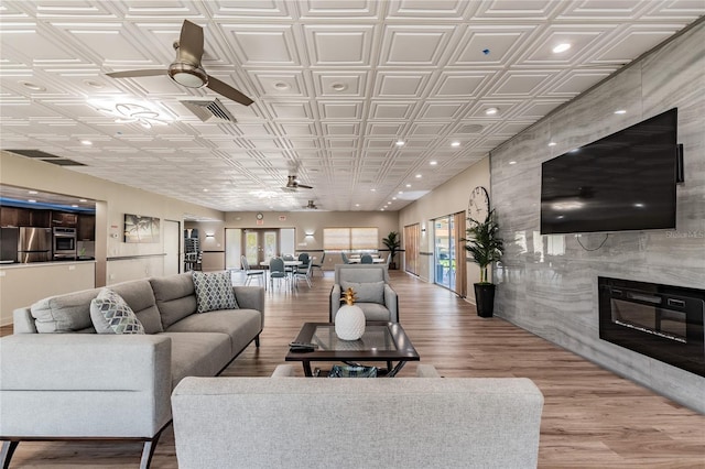 living room with hardwood / wood-style floors, ceiling fan, and a high end fireplace