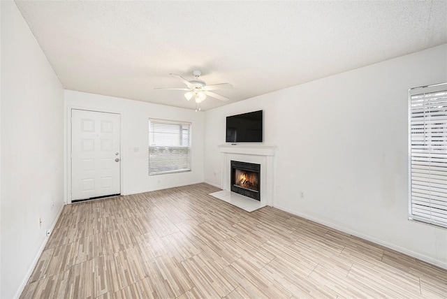 unfurnished living room featuring ceiling fan, a textured ceiling, and light wood-type flooring