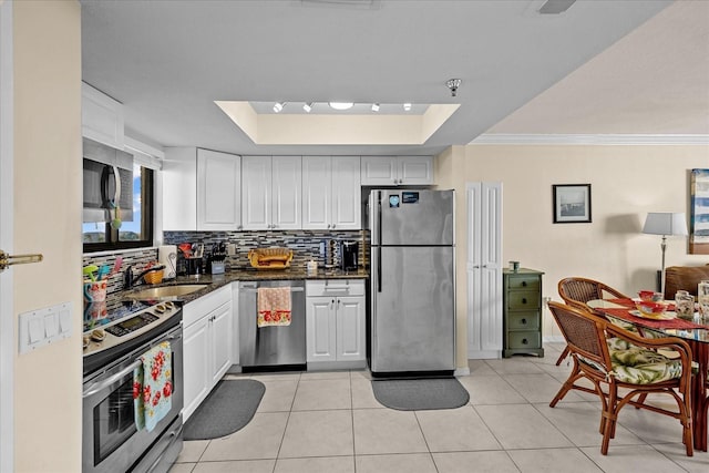 kitchen featuring appliances with stainless steel finishes, a raised ceiling, crown molding, sink, and white cabinets