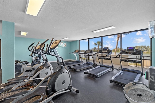 gym with floor to ceiling windows and a textured ceiling