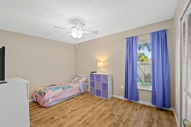 bedroom with a textured ceiling, light hardwood / wood-style flooring, a closet, and ceiling fan