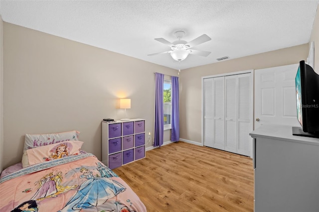 bedroom featuring ceiling fan, light hardwood / wood-style floors, a closet, and a textured ceiling