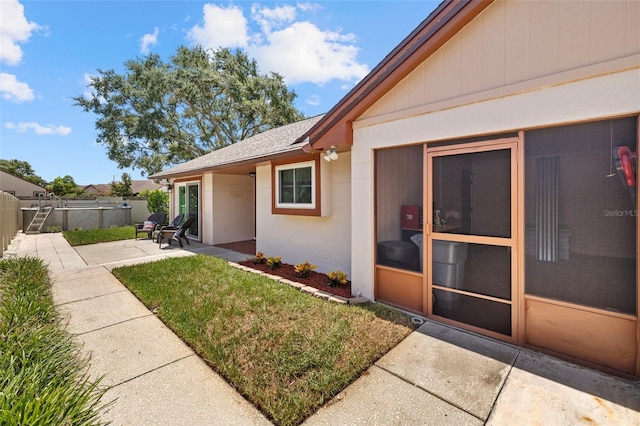 doorway to property featuring a patio area and a lawn