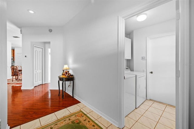 corridor with separate washer and dryer and light tile patterned floors