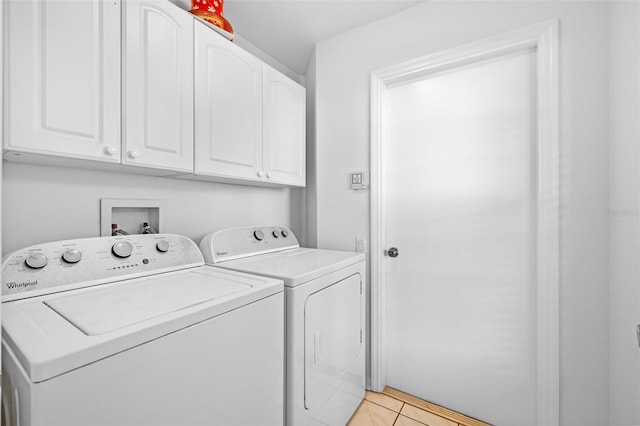 clothes washing area featuring cabinets, light tile patterned floors, and washing machine and clothes dryer