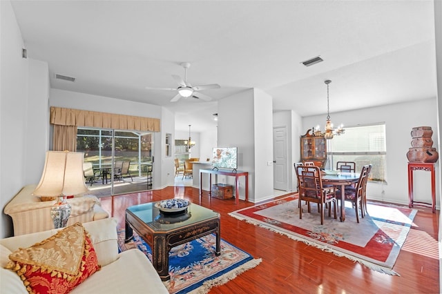 living room with vaulted ceiling, dark wood-type flooring, and ceiling fan with notable chandelier