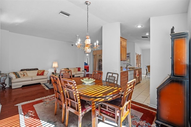 dining space with light hardwood / wood-style flooring, a chandelier, and sink