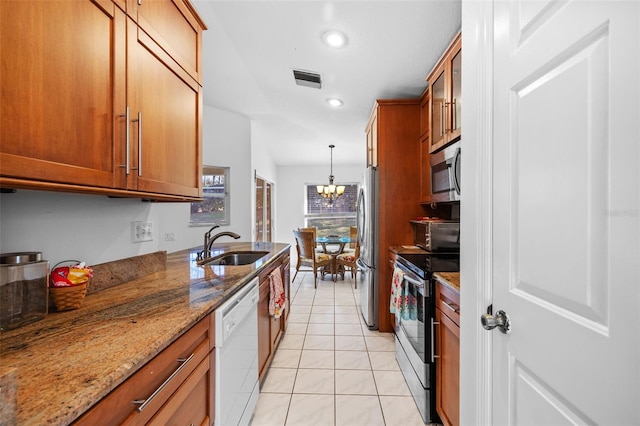 kitchen with stone counters, hanging light fixtures, sink, light tile patterned flooring, and stainless steel appliances