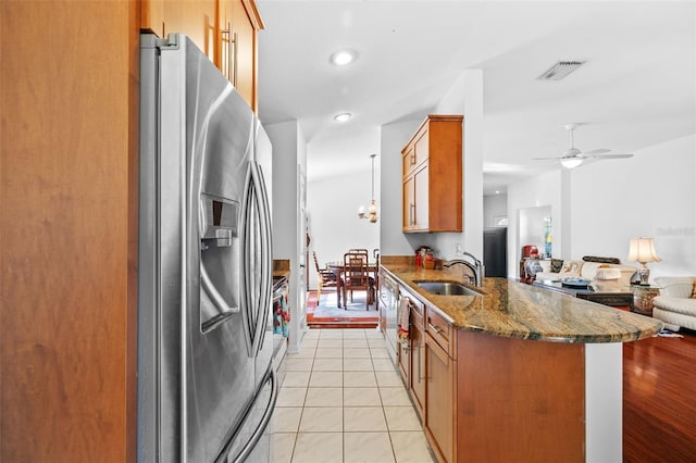 kitchen with ceiling fan, sink, stainless steel fridge with ice dispenser, dark stone countertops, and light tile patterned floors