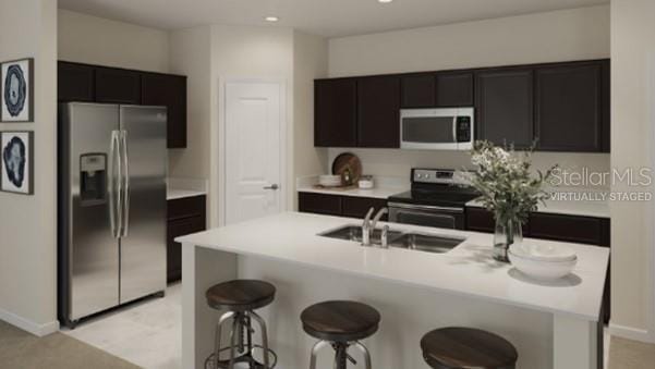 kitchen featuring a kitchen breakfast bar, sink, stainless steel appliances, and a center island with sink