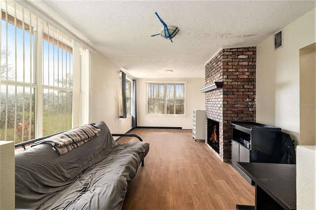 living room with a textured ceiling, a healthy amount of sunlight, light wood-type flooring, and a fireplace