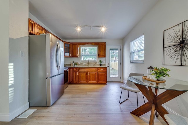 kitchen featuring appliances with stainless steel finishes, sink, track lighting, and light hardwood / wood-style floors