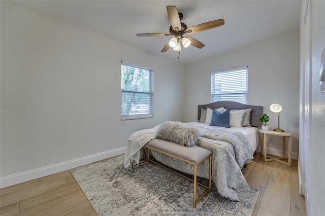 bedroom with ceiling fan, multiple windows, and light hardwood / wood-style flooring