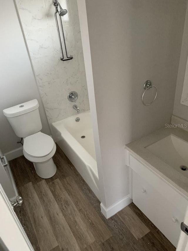 full bathroom featuring hardwood / wood-style flooring, tiled shower / bath combo, toilet, and vanity