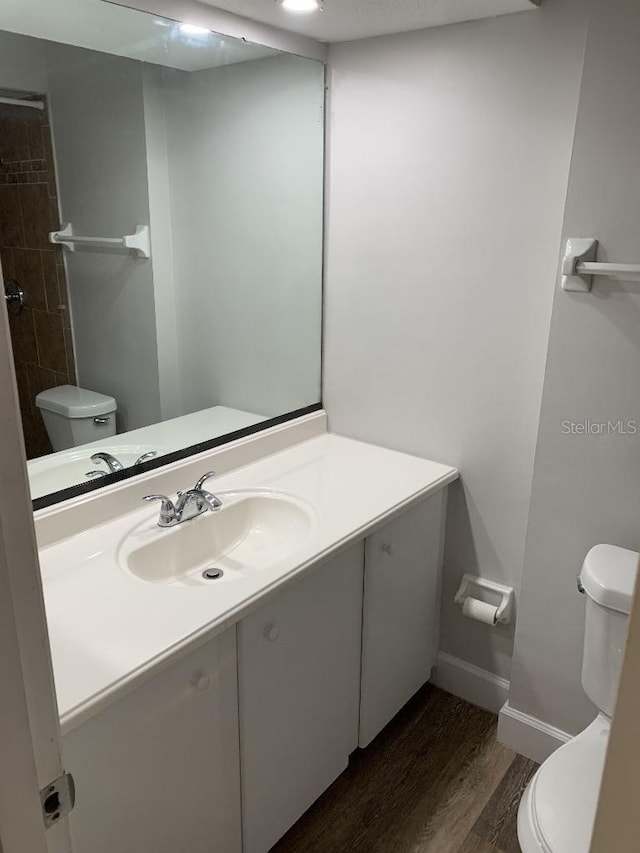 bathroom featuring toilet, vanity, and hardwood / wood-style flooring