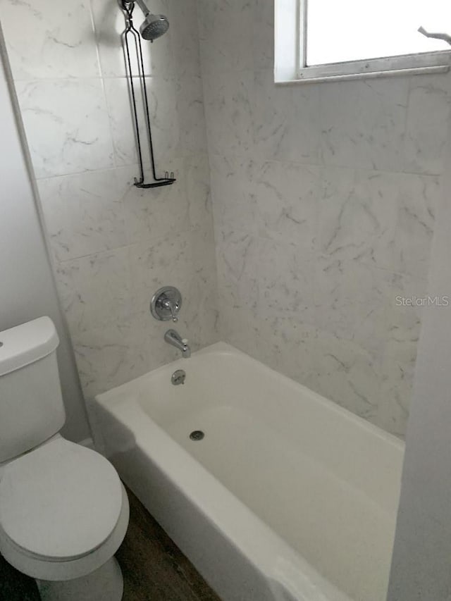 bathroom featuring tiled shower / bath combo and toilet