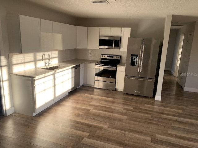 kitchen featuring sink, stainless steel appliances, hardwood / wood-style floors, a textured ceiling, and white cabinets