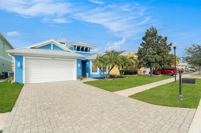 view of front of house with central AC unit, a garage, and a front lawn