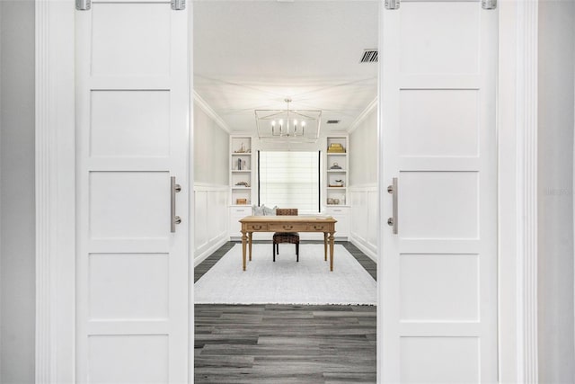 interior space featuring a notable chandelier, built in shelves, dark hardwood / wood-style flooring, and crown molding