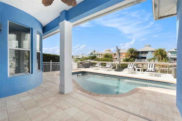 view of swimming pool with ceiling fan, a patio area, and a hot tub