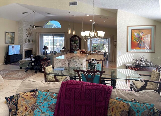 living room with an inviting chandelier, a textured ceiling, lofted ceiling, a fireplace, and light tile patterned floors