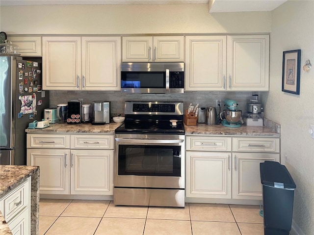 kitchen with decorative backsplash, light tile patterned flooring, light stone counters, and appliances with stainless steel finishes