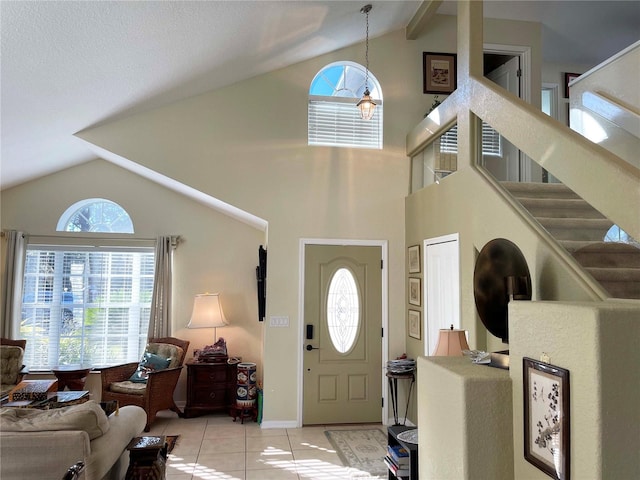 tiled entryway with a notable chandelier, a healthy amount of sunlight, and vaulted ceiling