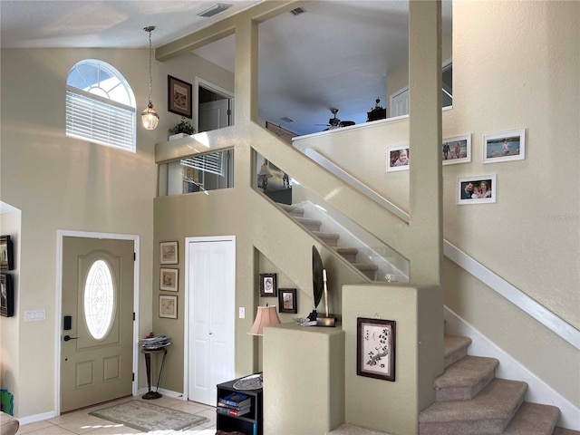 tiled entryway with ceiling fan and high vaulted ceiling