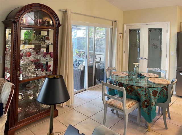 dining area with light tile patterned floors, french doors, and vaulted ceiling