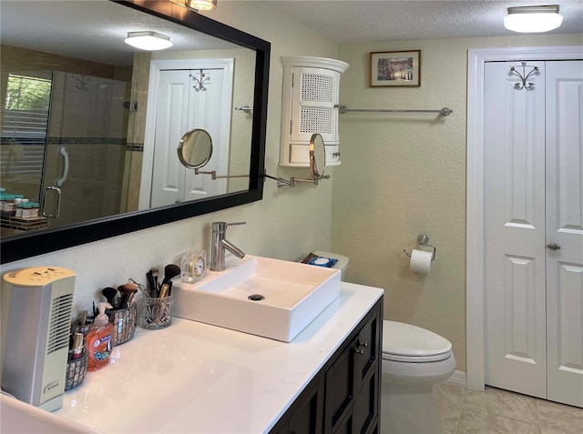 bathroom with tile patterned floors, a textured ceiling, toilet, a shower with door, and vanity