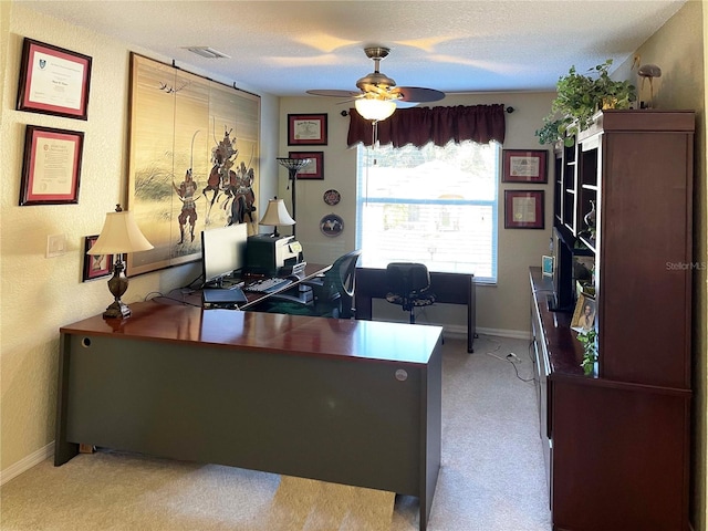 carpeted home office with ceiling fan and a textured ceiling