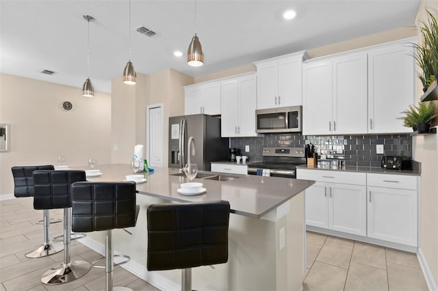 kitchen with a kitchen breakfast bar, white cabinetry, pendant lighting, and stainless steel appliances