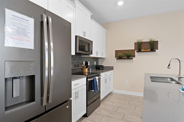 kitchen featuring decorative backsplash, stainless steel appliances, white cabinetry, and sink