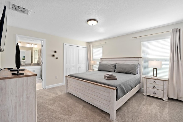 carpeted bedroom featuring a textured ceiling and connected bathroom