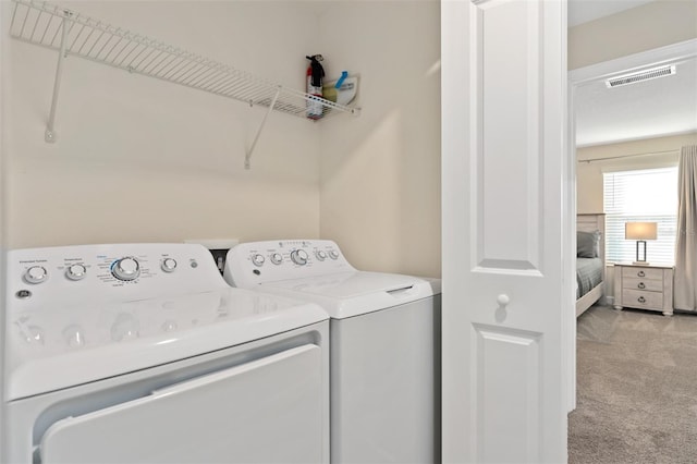 clothes washing area featuring separate washer and dryer and light colored carpet