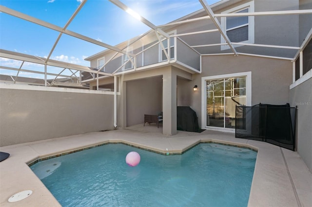 view of swimming pool featuring glass enclosure and a patio area