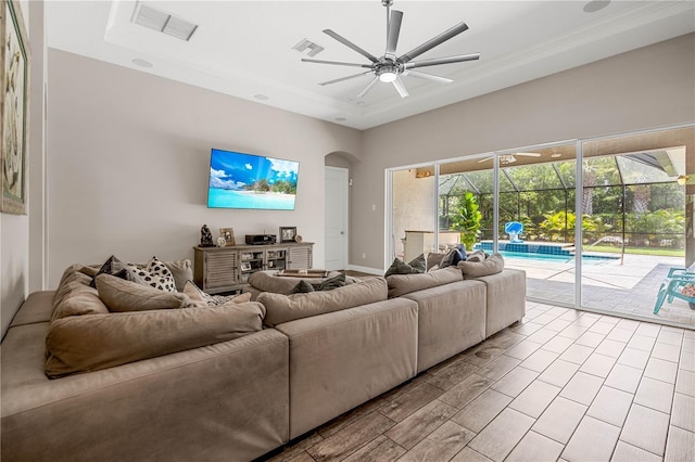 living room featuring a tray ceiling, ceiling fan, and ornamental molding